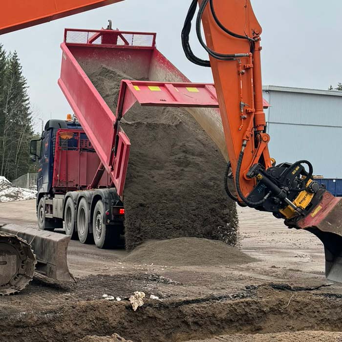 Kuljetusrekka kaatamassa hiekkaa maahan työmaalla
