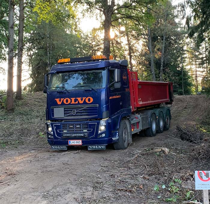 Sininen Volvo-kuljetusrekka ajamassa metsätiellä